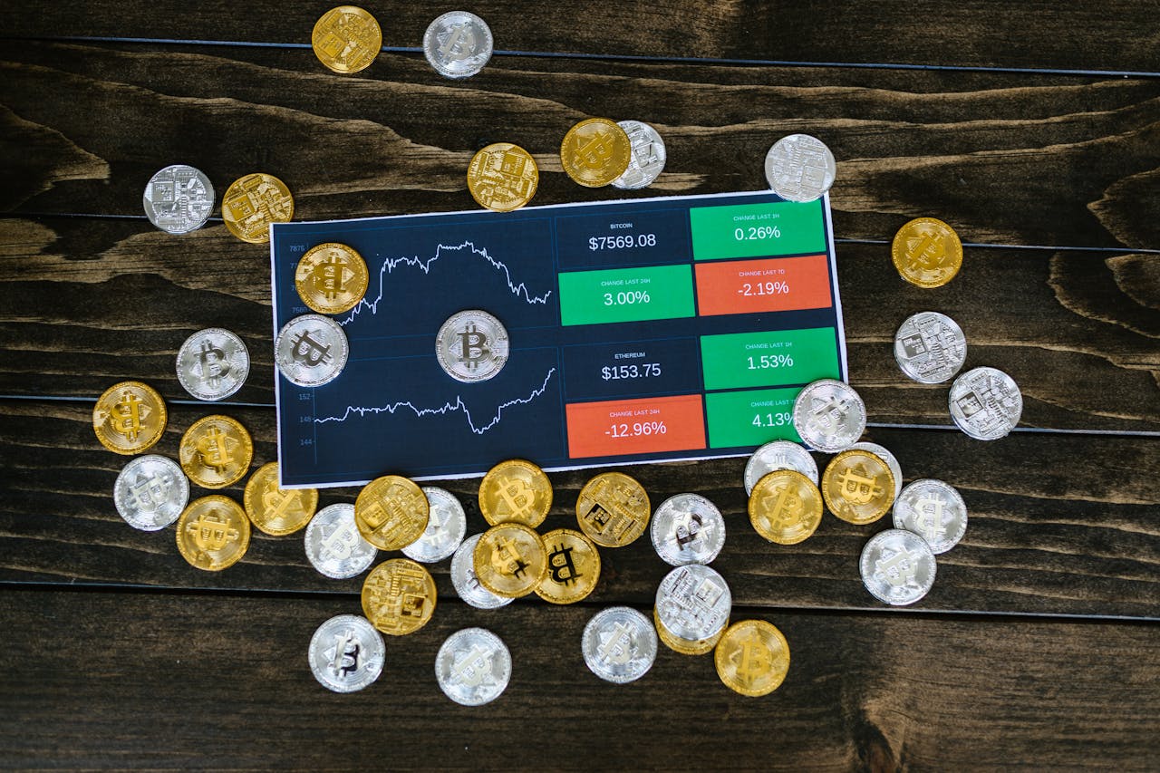 Bitcoin coins scattered around a stock chart on a dark wooden table, symbolizing cryptocurrency investment.